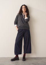 Woman wearing a grey sweater and dark blue wide leg cargo jeans with brown loafers