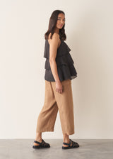 Woman wearing black layered halter top with brown linen trousers