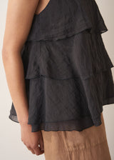 Woman wearing black layered halter top with brown linen trousers