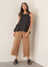 Woman wearing black layered halter top with brown linen trousers