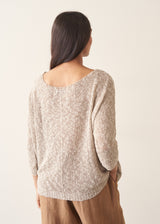 Woman wearing a beige lightweight knit with camel linen wide leg trousers, against a beige background