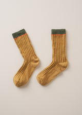 Heavy knit socks in a mustard yellow wool blend, with retro orange and green ankle stripes, on a beige background