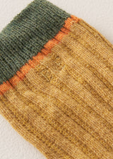 Close up of heavy knit socks in a mustard yellow wool blend, with retro orange and green ankle stripes