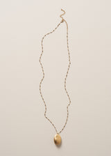 Beaded gold chain necklace with pendant on a beige background