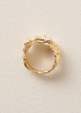 Side view of a large, textured molten gold ring on a beige background