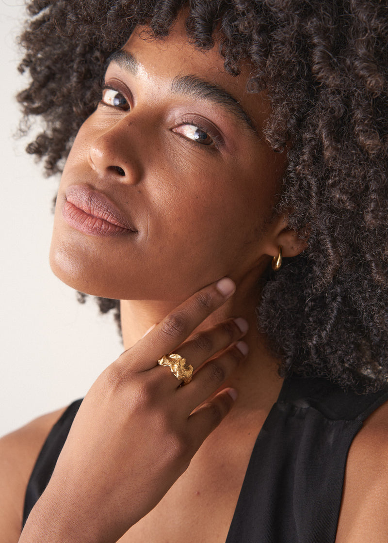 Close-up of a woman's wearing a large, textured molten gold statement ring