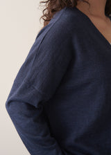 Woman wearing a navy lightweight cardigan against a beige background