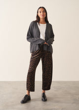 Woman wearing a light charcoal grey cardigan with leopard print trousers and a white t-shirt.