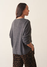 Woman wearing a light charcoal grey cardigan with leopard print trousers and a white t-shirt.