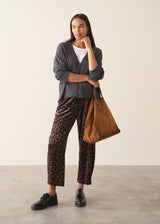 Woman wearing a light charcoal grey cardigan with leopard print trousers and a white t-shirt.