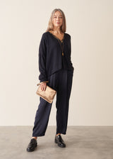 A woman wearing a dark navy light cardigan with navy satin trousers