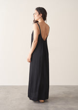 Woman wearing a black dress with an open back against a plain background