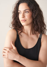Woman wearing a black tank top against a plain background