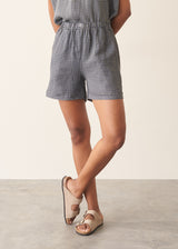 Woman wearing a checked linen top and matching checked linen shorts against a plain background