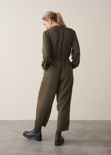 Woman wearing dark khaki relaxed fit jumpsuit with pocket and waist tie