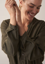 Woman wearing dark khaki relaxed fit jumpsuit with pocket and waist tie