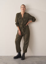 Woman wearing dark khaki relaxed fit jumpsuit with pocket and waist tie