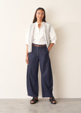 Woman wearing dark blue barrel leg denim jeans with a white cotton shirt.