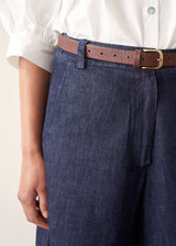 Woman wearing dark blue barrel leg denim jeans with a white cotton shirt.