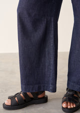 Woman wearing dark blue barrel leg denim jeans with a white cotton shirt.