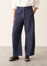 Woman wearing dark blue barrel leg denim jeans with a white cotton shirt.