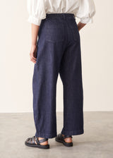 Woman wearing dark blue barrel leg denim jeans with a white cotton shirt.