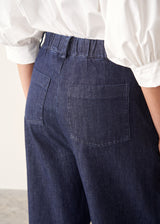 Woman wearing dark blue barrel leg denim jeans with a white cotton shirt.
