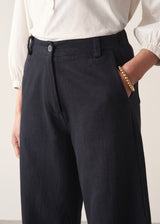 Close up of woman wearing a white shirt and cropped black barrel-leg cotton denim jeans