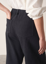 Woman wearing a white shirt and black, cropped, barrel-leg denim jeans