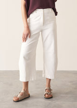 Woman wearing white cropped barrel leg jeans with plum short sleeve top