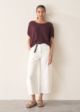 Woman wearing white cropped barrel leg jeans with plum short sleeve top