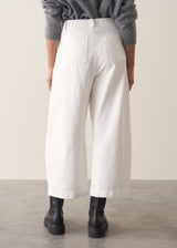 Person wearing grey cardigan and white denim barrel leg jeans