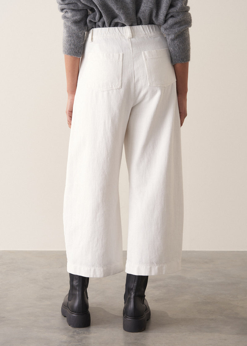 Person wearing grey cardigan and white denim barrel leg jeans