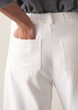 Person wearing grey cardigan and white denim barrel leg jeans