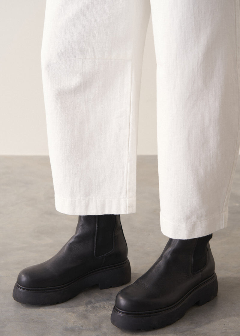 Person wearing grey cardigan and white denim barrel leg jeans