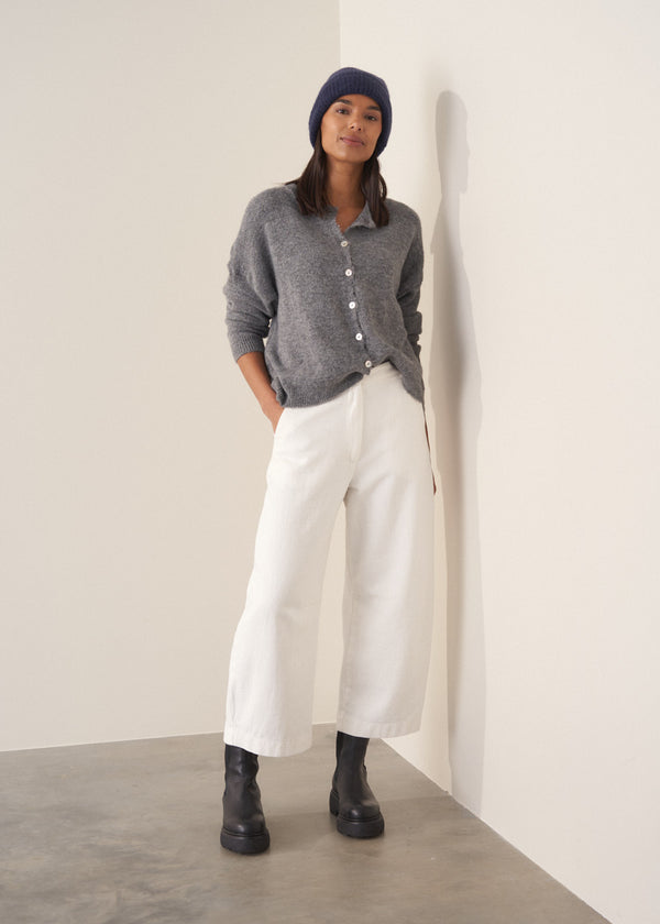Person wearing grey cardigan and white denim barrel leg jeans