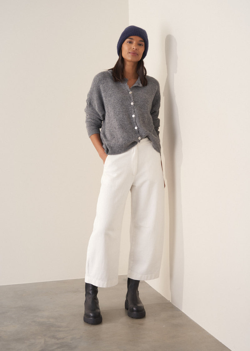 Person wearing grey cardigan and white denim barrel leg jeans