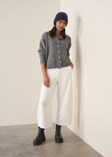 Person wearing grey cardigan and white denim barrel leg jeans