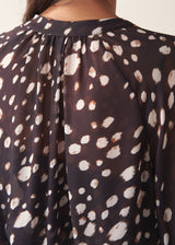A woman wearing a dark brown deer print  blouse with checked trousers and a dark grey blazer