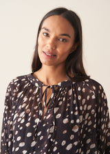 A woman wearing a dark brown deer print  blouse with checked trousers and a dark grey blazer
