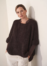 Woman wearing an oversized brown jumper with white trousers