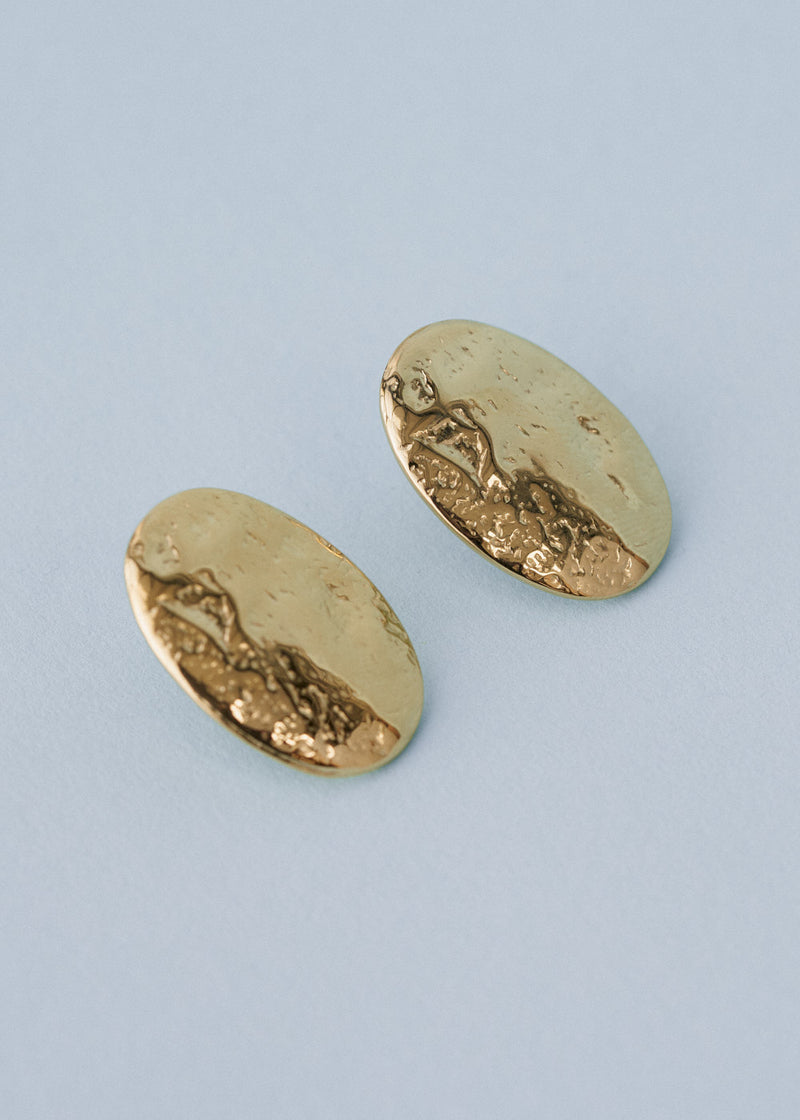 Gold hammered stud earrings on blue background
