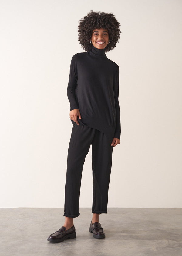 Woman wearing a black turtleneck sweater sweater against a neutral background