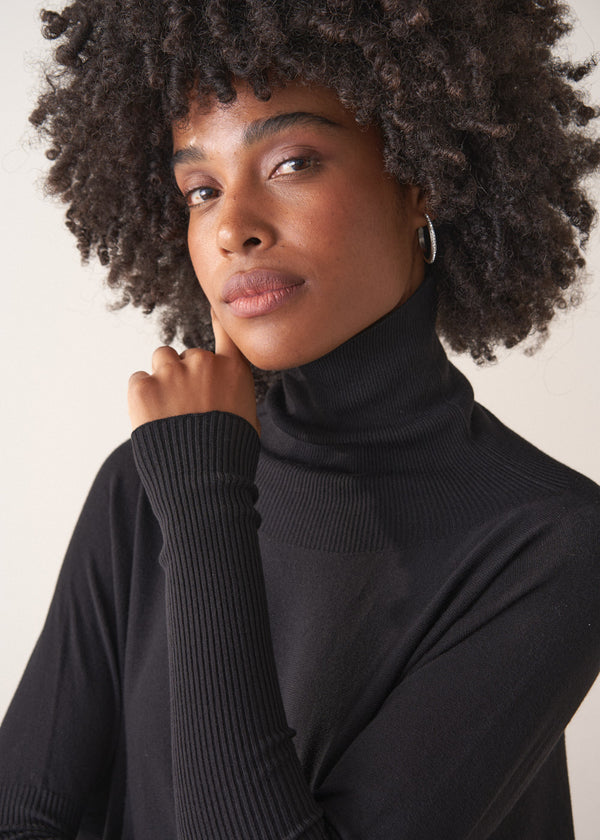 Woman wearing a black turtleneck sweater sweater against a neutral background
