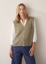 Woman wearing khaki green sleeveless knit waistcoat with blue jeans