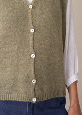 Woman wearing khaki green sleeveless knit waistcoat with blue jeans