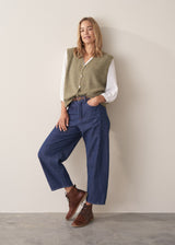 Woman wearing khaki green sleeveless knit waistcoat with blue jeans