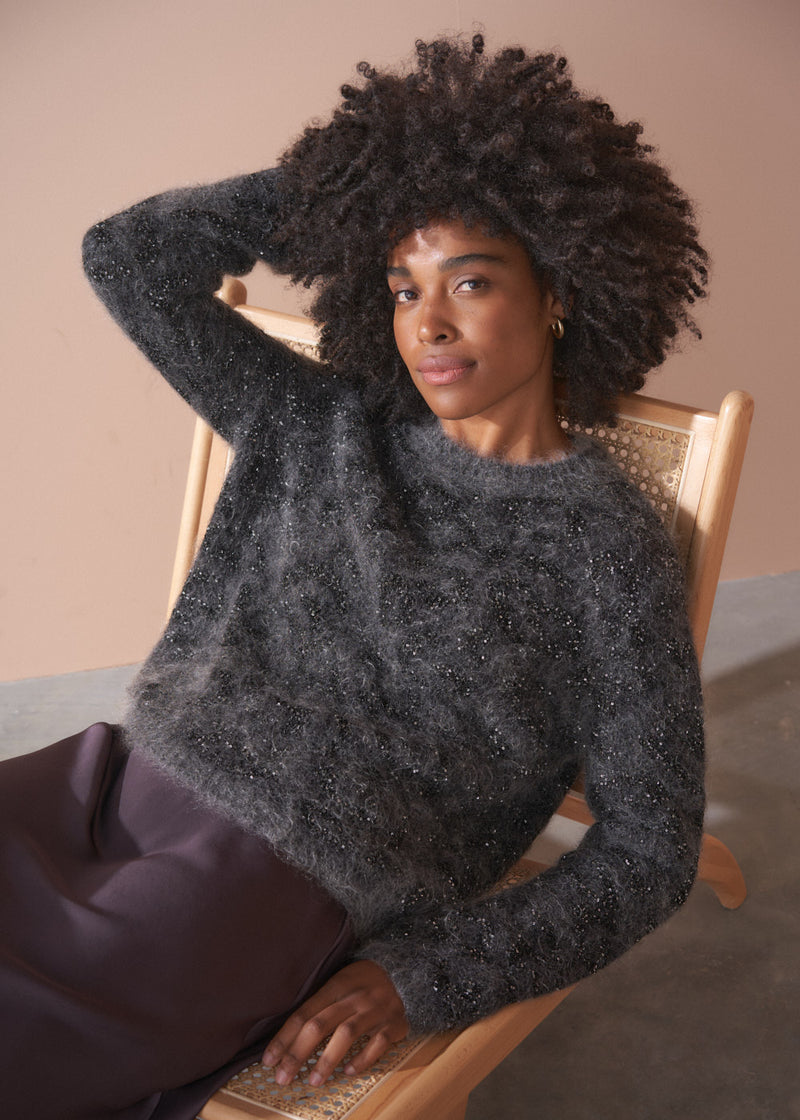 Woman wearing a dark grey fluffy textured sweater with sequin detail.