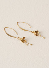 Gold blossom drop earrings on a beige background