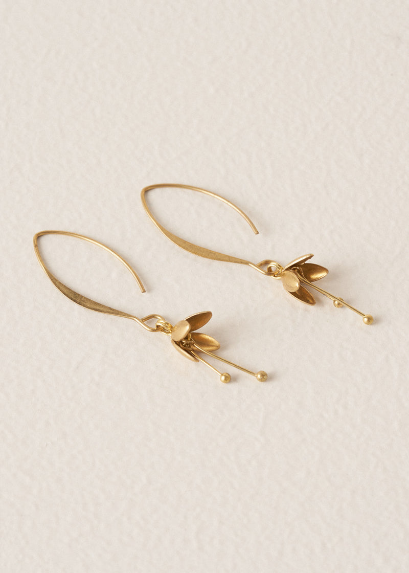 Gold blossom drop earrings on a beige background